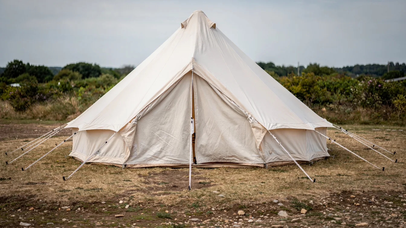 Close view of a sturdy canvas bell tent with central pole, zipped doorway and pegged guy lines